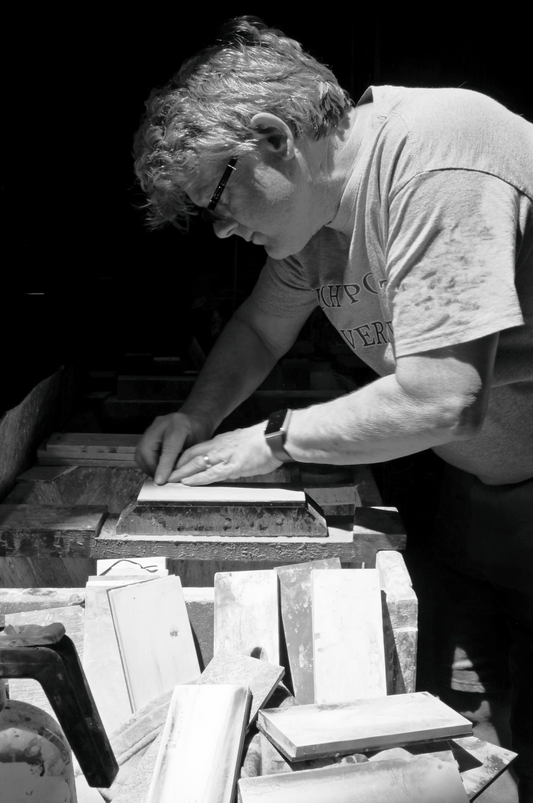 Man sharpens chisel on a whetstone with lapping plates in the foreground